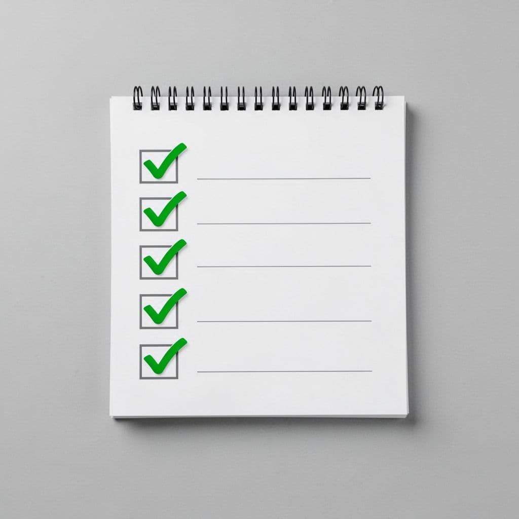 Clean modern illustration of a simple checklist pad with five green checkmarks next to blank lines on a desk surface with subtle shadow.